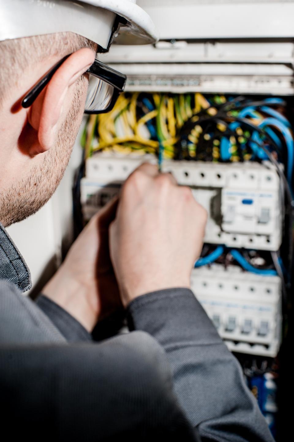Elektrikář zapojuje vodiče v domovním rozvaděči